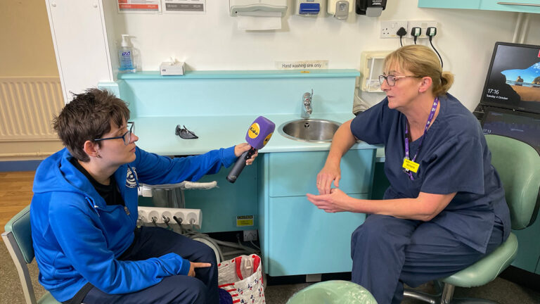 Carly holding a microphone while interviewing her dentist